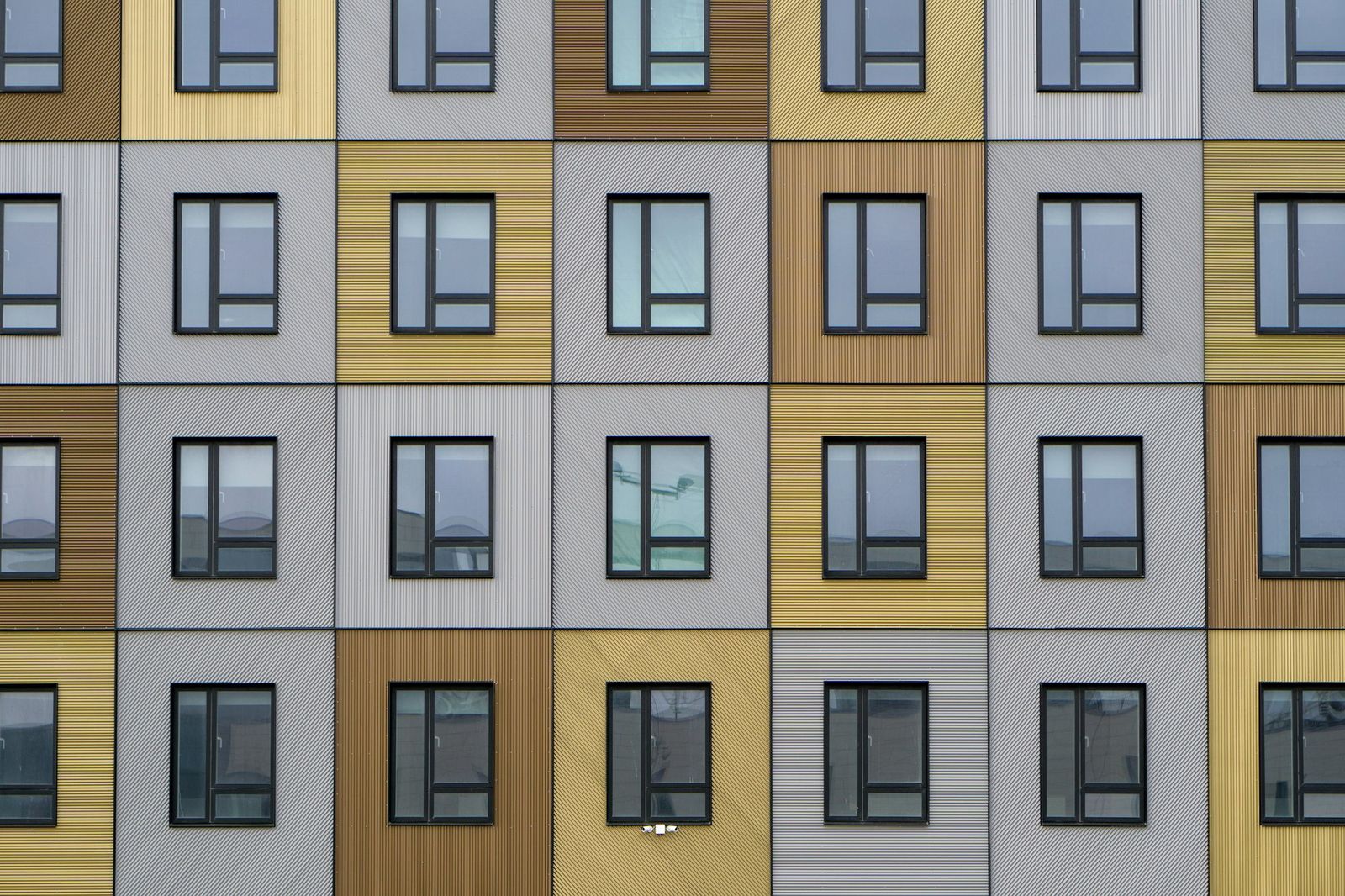 A building facade of wooden and white panels, with windows set in a regular grid.